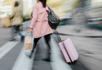 Blurred image of woman with suitcase and bag