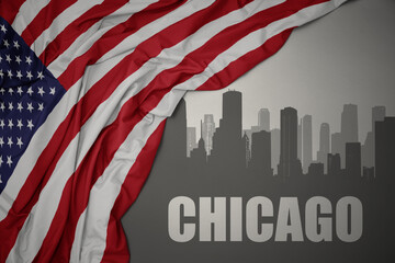 abstract silhouette of the city with text chicago near waving national flag of united states of america on a gray background.