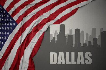 abstract silhouette of the city with text dallas near waving national flag of united states of america on a gray background.