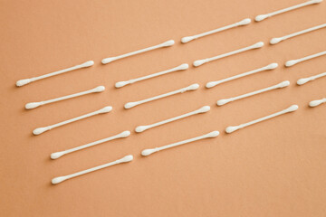 horizontal rows of cotton swabs on beige background, top view.