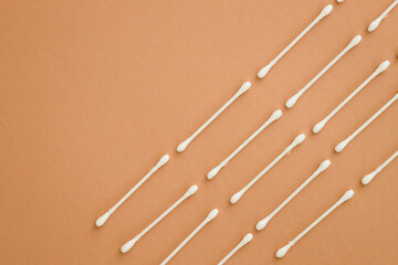 horizontal rows of cotton swabs on beige background, top view.