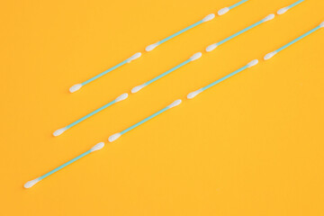 Flat lay composition with cotton swabs on yellow background. Top view ear sticks