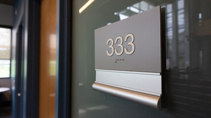 An office number sign on the glass wall