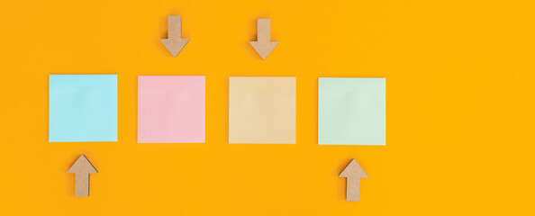 Colorful sticky notes and different wooden arrows on yellow background.