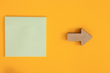Colorful sticky notes and different wooden arrows on yellow background.