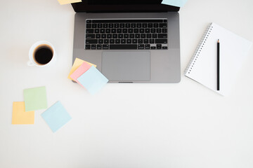 Office desk with sticky note,laptop computer, pencil and cup of coffee on white wood table background.