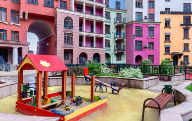 Fototapeta na wymiar Empty children playground park with sandbox and playground equipment. Outdoor playground with house building facade mixed-use urban multi-family residential district area settings.