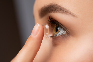 Beautiful woman holds contact lens on her finger. Eye care and the choice between the means to...
