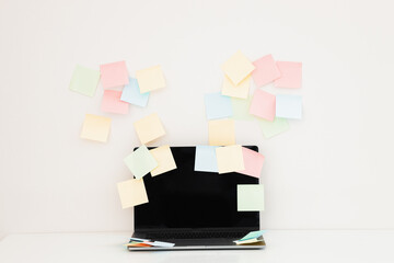 Modern laptop and different sticky notes on white wall