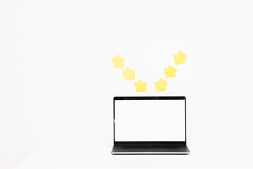 White blank screen laptop on the wood table with yellow blank sticky notes on wall background