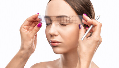 Make-up artist makes markings with white pencil for eyebrow and paints eyebrows. Professional...