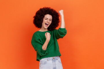 Portrait of happy excited woman with Afro hairstyle wearing green casual style sweater celebrating...