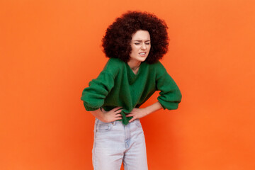 Portrait of woman with Afro hairstyle wearing green casual style sweater suffering from strong...