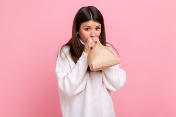 Nervous girl feeling sick, breathing into paper bag to improve state of health, overcoming stress,...