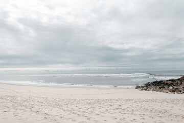 Beautiful sandy beach overlooking the ocean and rocks with overcast skies
