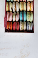 Colorful macaroons in a gift box on a white table.