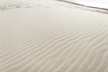 White sandy beach with waves of sand by the ocean. Sand texture