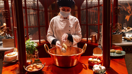 Beautiful girl cook in a robe and mask prepares a delicious national dish