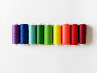 sewing threads arranged in rainbow order on white background