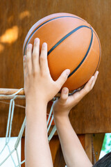 close view of hands throwing a ball into a basketball basket, teenage boy playing at home in the backyard, outdoor activities on summer vacation