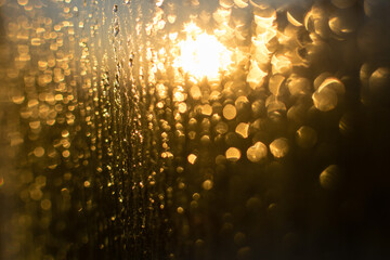 Blurred bokeh rain drops on glass window viewing skyline on a sunrise. Abstract rain drop or...