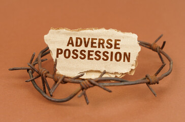 On a brown surface, barbed wire and a cardboard sign with the inscription - Adverse Possession