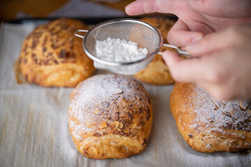 spreading powdered sugar on almond coissants