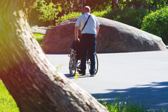 A man rolls a wheelchair with a disabled person