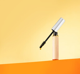 Castor oil for eyelashes and eyebrows in a vial with a brush on an orange background. Beauty concept, eyelash and eyebrow care, wellness, growth, eyelash extensions. Copy space