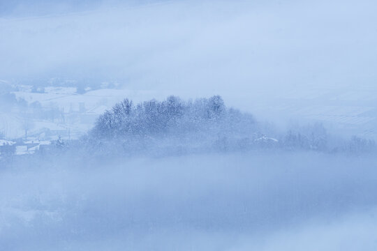 Brianza covered in fresh snow and fog in the early morning, near the town of Brivio, Italy - December 2021.