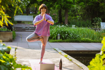 An old slender woman does yoga in the park online