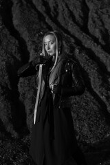 Obraz premium Beautiful woman in leather jacket with vintage sword in black and white