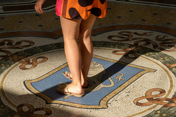 Legs of a woman spinning on the bull mosaic for making a wish in Milan Italy