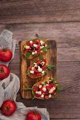 Bruschetta with tomatoes, Feta cheese and arugula on a dark wood table. Top view. Copy space. 