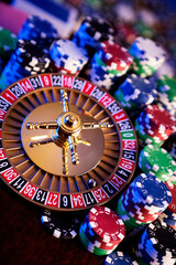 Casino theme.  Roulette wheel and poker chips on  colorful bokeh background.