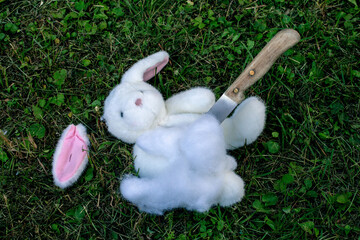 stuffed bunny lying on the floor destroyed with a knife
