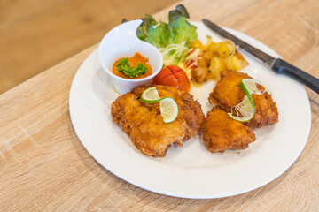 selective focus, Deep Fried Dolly Fish Steak with potato grill in white plate on wood table,Two pieces of battered cod fish on a plate with french fries, fish and chips