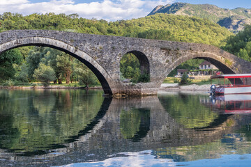 ponte de pedra espelhada no lago Shkodra em Montenegro - obrazy, fototapety, plakaty