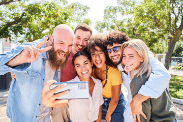Obraz premium Woman taking mobile phone selfie with a multiracial group of friends. 