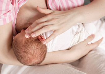 A mother is breastfeeding her little baby. Newborn, breastfeeding. Top view selective soft focus