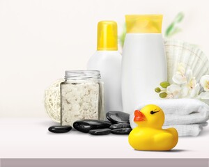 Baby accessories for bathing on table. Shampoo and shower gel bottles, duck toys, towel.