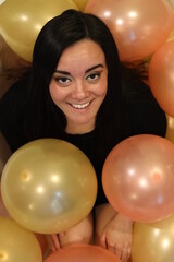 cheerful woman surrounded by balloons at a party
