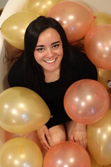 cheerful woman surrounded by balloons at a party