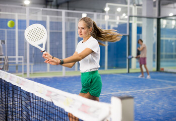 Portrait of a confident fifteen-year-old girl tennis player engaged in the popular sport of padel...