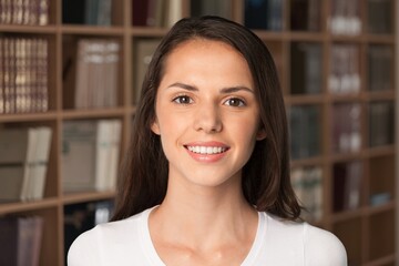A young beautiful teenager girl smile looking at camera in university library, concept of higher...
