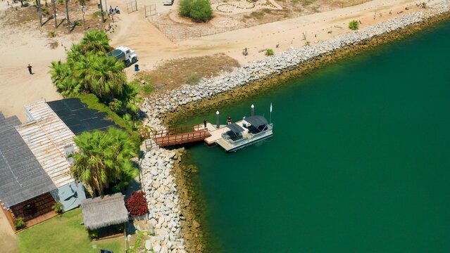 2020:SAN JOSE DEL CABO MEXICO.Two Humans Stepping Onto Boat Off The Rocky Shore Of An Ocean