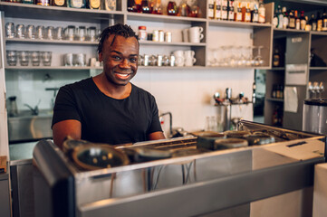 Portrait of an african american male coffee shop owner barista working in a care.