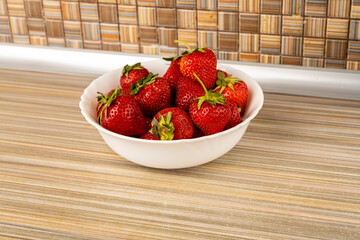 Ripe and juicy strawberries in a plate on the table.