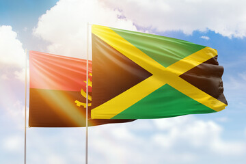 Sunny blue sky and flags of jamaica and angola