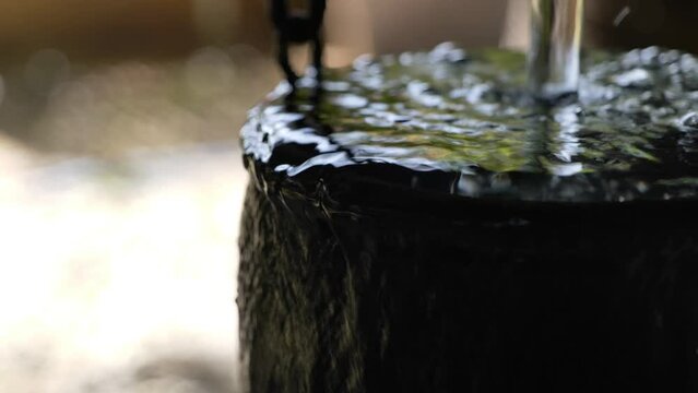 Selective focus at water overflow from clay pot or hanging bowl. Decorative spillway fountain bowl water feature.